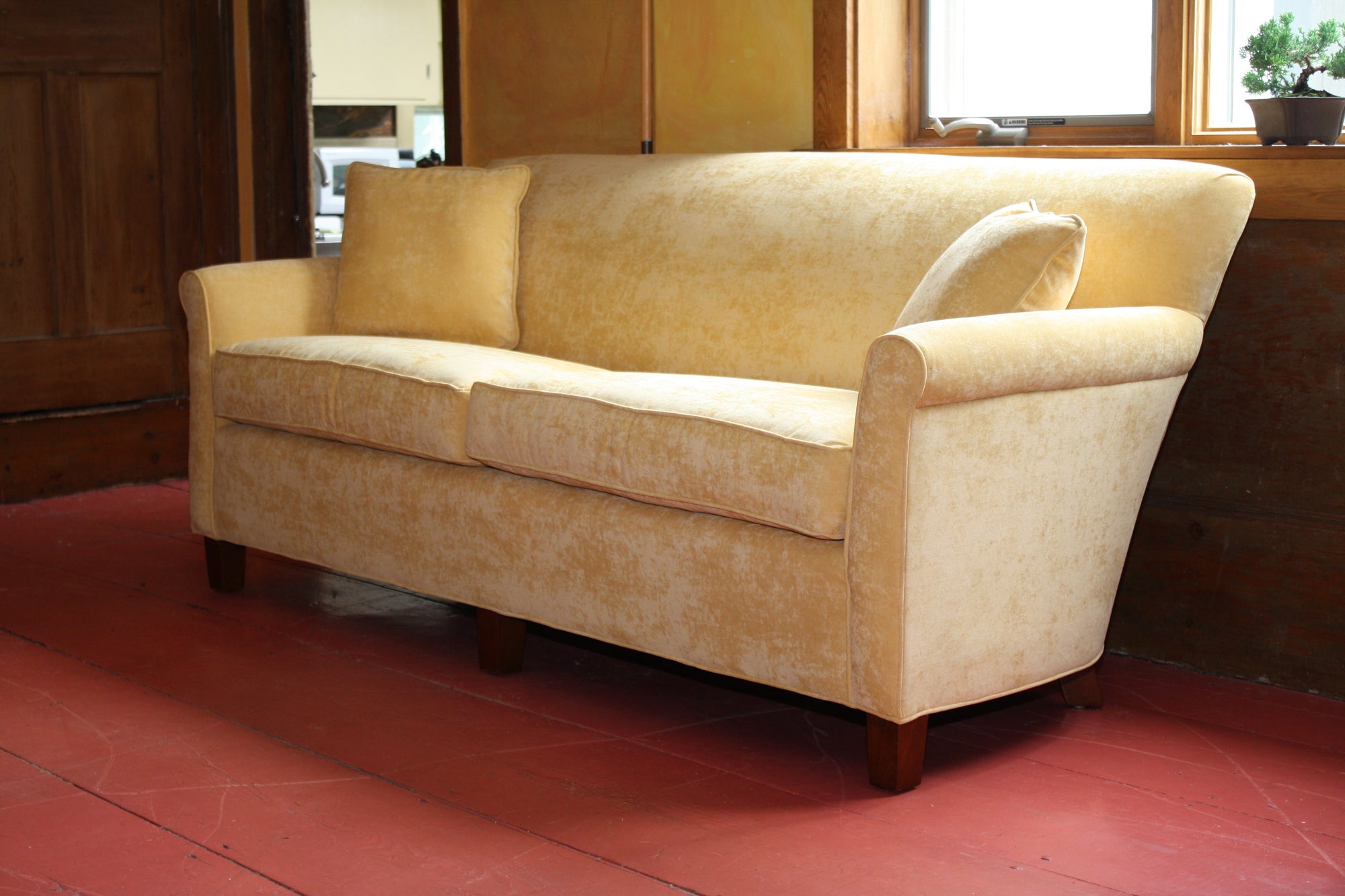A small yellow sofa with a luxurious buttery colored fabric